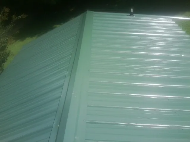 New green metal panels meeting at the ridge of a roof — Flat Roof Repair work by our crew in Chico