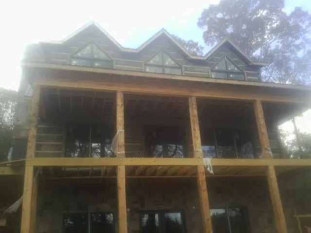 Dormers and porch framing on a large log home under construction — Roof Coating work by our crew in Chico